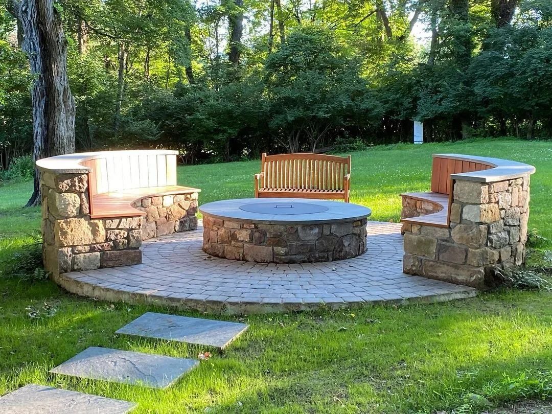Round stone fire pit with flagstone cap and curved stone seating walls