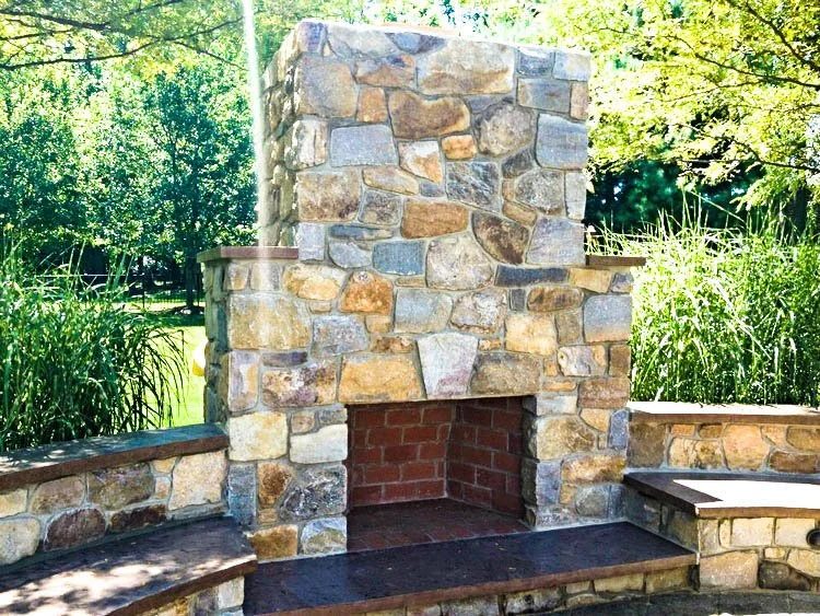 Outdoor real-stone fireplace flanked by built-in stone benches
