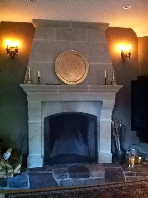 Indoor carved limestone fireplace surround with a fieldstone hearth