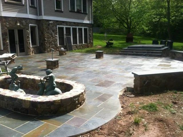 Flagstone entertainment patio with a curved stone pond and fountain
